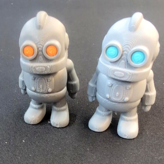 Two articulated 3D-printed robot minis with orange and turquoise eyes