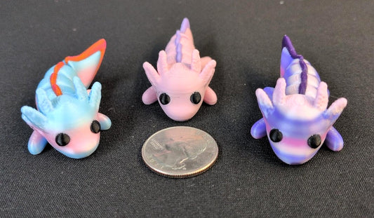Three colorful articulated 3D printed Axolotls beside a quarter for scale
