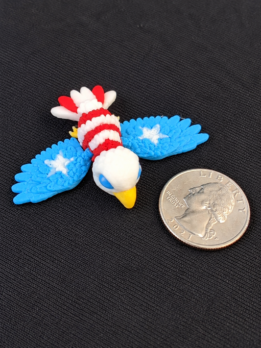 Red, white and blue 3D printed American eagle mini beside a quarter for scale