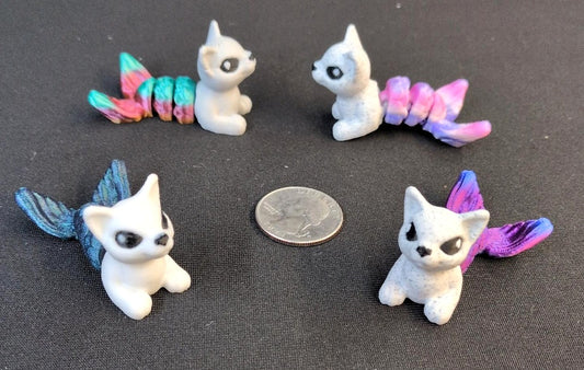 Four colorful 3D printed Cat Fish figures beside a quarter for scale