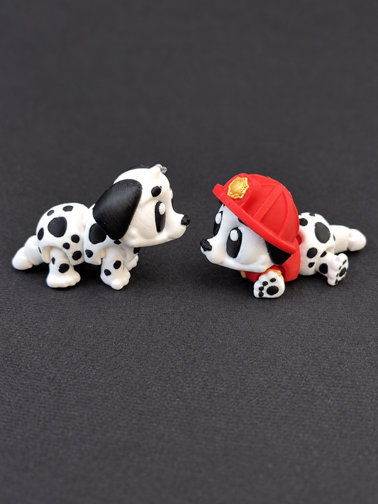 Two articulated 3D-printed Dalmatians, one without a hat and one wearing a red firefighter hat