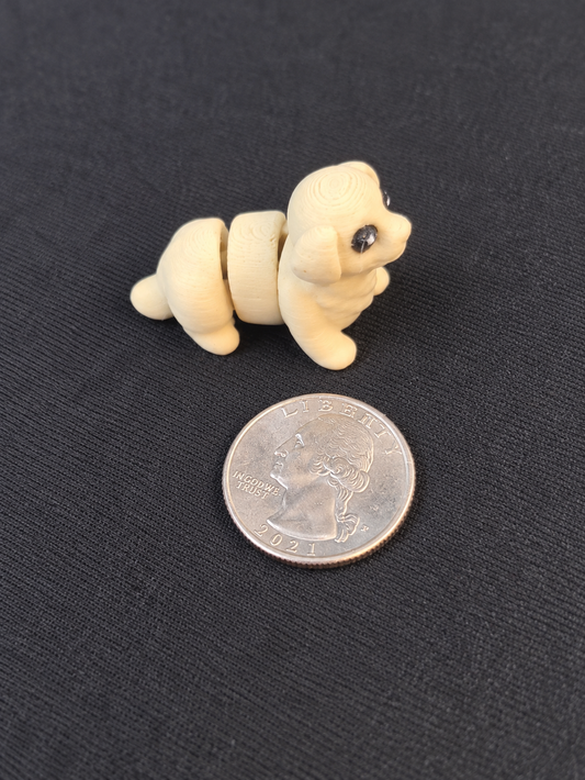 Cream-colored articulated Golden Retriever mini beside a quarter for scale