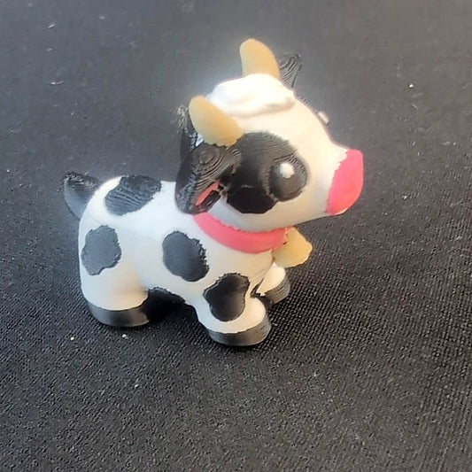 Non-articulated cow statue with black spots, small horns, and pink nose