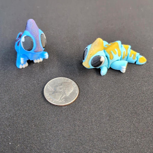 Two colorful 3D printed Parasaur figures beside a quarter for scale