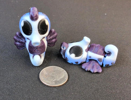 Two blue and purple articulated 3D printed Seahorse poses beside a quarter for scale