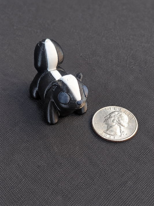 Black and white 3D printed skunk mini beside a quarter for scale
